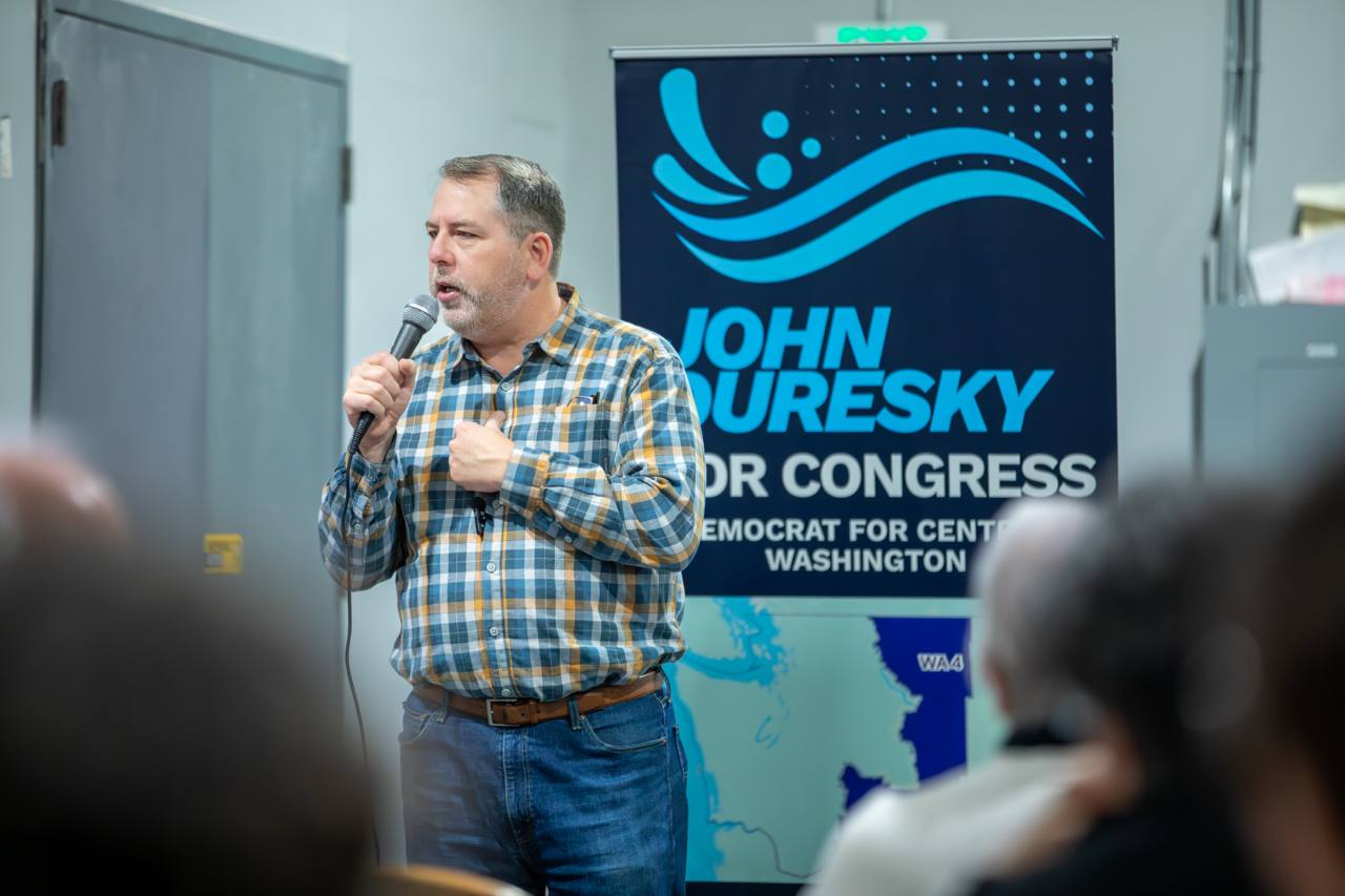John speaking at a town hall